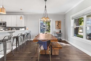 Una cocina moderna con una isla grande, taburetes de bar y una lámpara colgante.