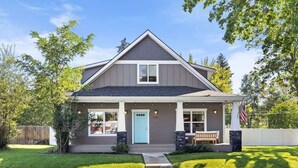 A two-story house with a front porch, a blue door, and a flag. - Family fun home with hot tub, arcade and zipline (Coeur d'Alene)