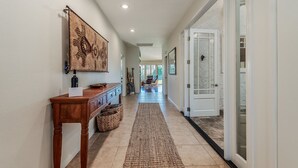 A hallway with a wooden console table, a woven rug, and a door with glass panels. - Endless views in Indian Wells!  Desert Horizons new and improved in 2024! (Indian Wells)
