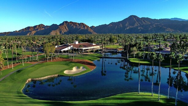 A golf course with a pond, palm trees, and mountains in the background. - Endless views in Indian Wells!  Desert Horizons new and improved in 2024! (Indian Wells)