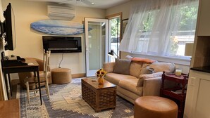 A living room with a sofa, ottoman, coffee table, and a TV mounted on the wall. - Charming Montauk Getaway centrally located  (Montauk)