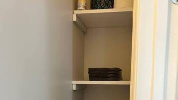 A closet with multiple shelves, some with folded clothes and a tissue box on the top shelf.