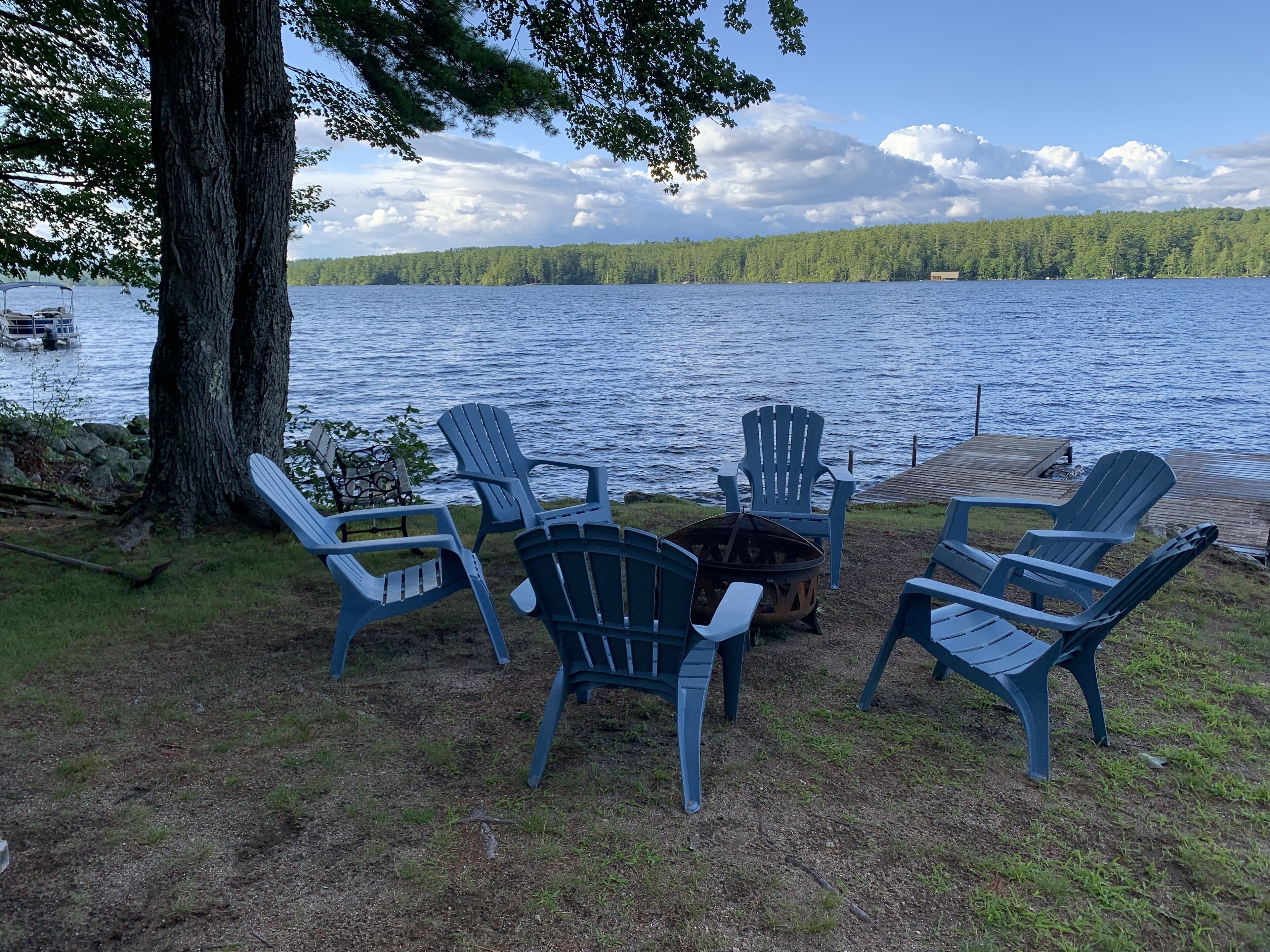 A lakeside seating area with Adirondack chairs and a fire pit.