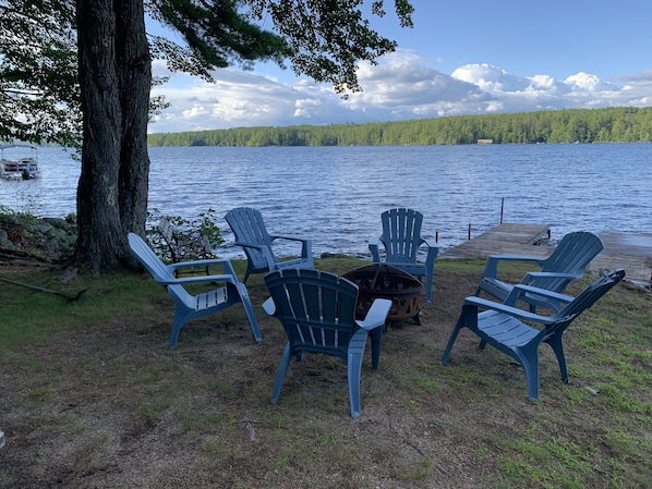 Sitzbereich am Seeufer mit Adirondack-Stühlen und einer Feuerstelle.