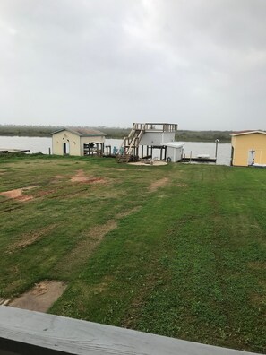 Una propiedad frente al lago con césped, un pequeño embarcadero y un edificio con escaleras.
