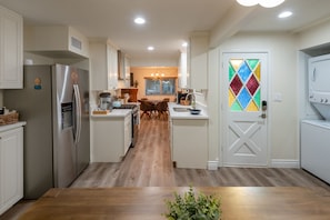 A modern kitchen with a central island, stainless steel appliances, and a colorful stained glass door.