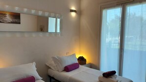 Une chambre d’hôtel avec deux lits, une grande fenêtre, un luminaire fixé au mur et un objet décoratif sur le mur.