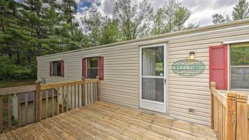 A single-story mobile home with a deck, a sliding glass door, and a 'Welcome' sign.
