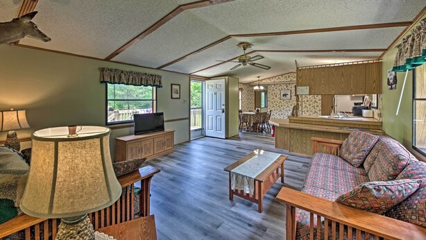 A spacious living room with a wooden floor, a sofa, a coffee table, and a television. - Secluded Woodsy Cabin: Hike, Fish, Hunt + ATV! (Arkdale)