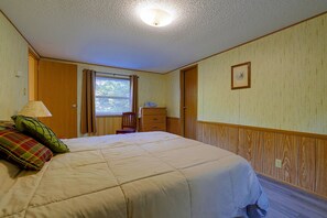 Une chambre à coucher avec un lit, une fenêtre, une chaise, une commode et un tableau au mur.