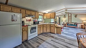 A spacious kitchen with wooden cabinets, a refrigerator, stove, and microwave. - Secluded Woodsy Cabin: Hike, Fish, Hunt + ATV! (Arkdale)