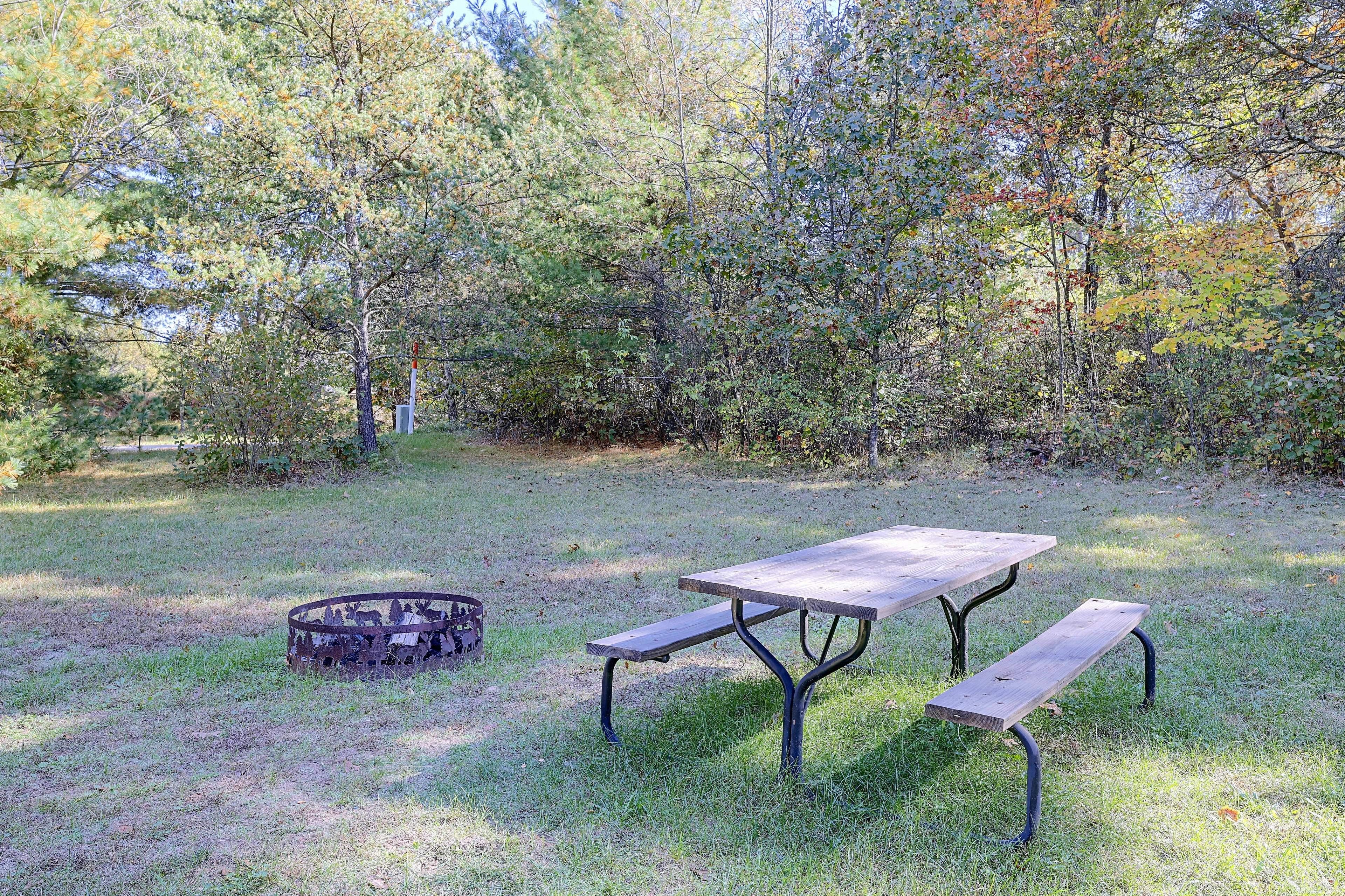 Una mesa de picnic con bancos en un área verde rodeada de árboles.