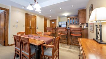 Un comedor con una mesa y sillas de madera, una cocina con armarios de madera y una lámpara de techo.