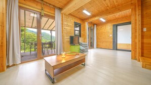 Un intérieur en bois avec une table en bois, un téléviseur et une vue sur la verdure à l’extérieur.