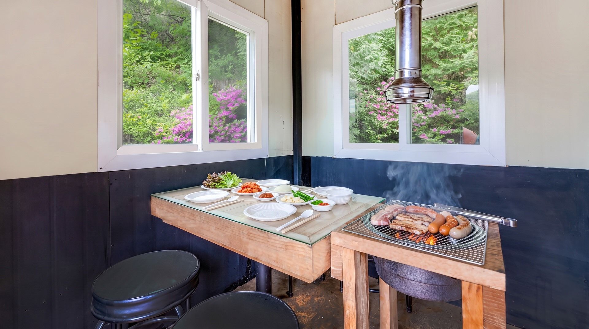A small kitchen area with a grill, dining table, and two stools.