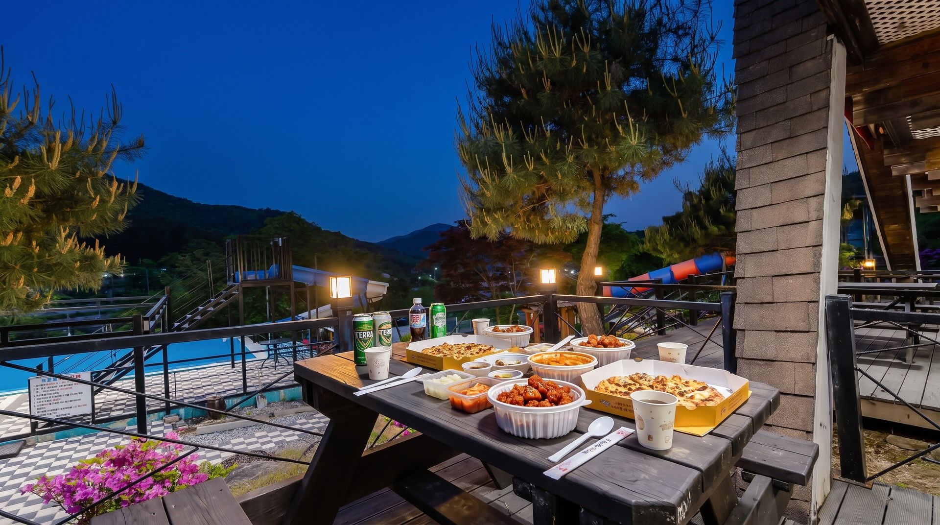 An outdoor dining area with a table set for a meal, overlooking a pool and mountains.