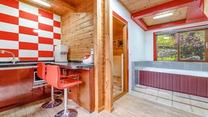 Een moderne keuken met een zwart-wit geruit spatwand, een koffieapparaat en rode barkrukken.