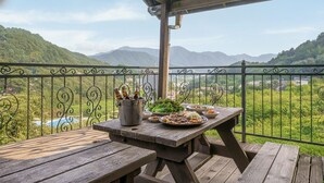 Une table de pique-nique en bois avec un gril en métal, entourée d’une clôture métallique. On y trouve des assiettes de nourriture, un seau rempli de bouteilles et une bouteille de sauce.