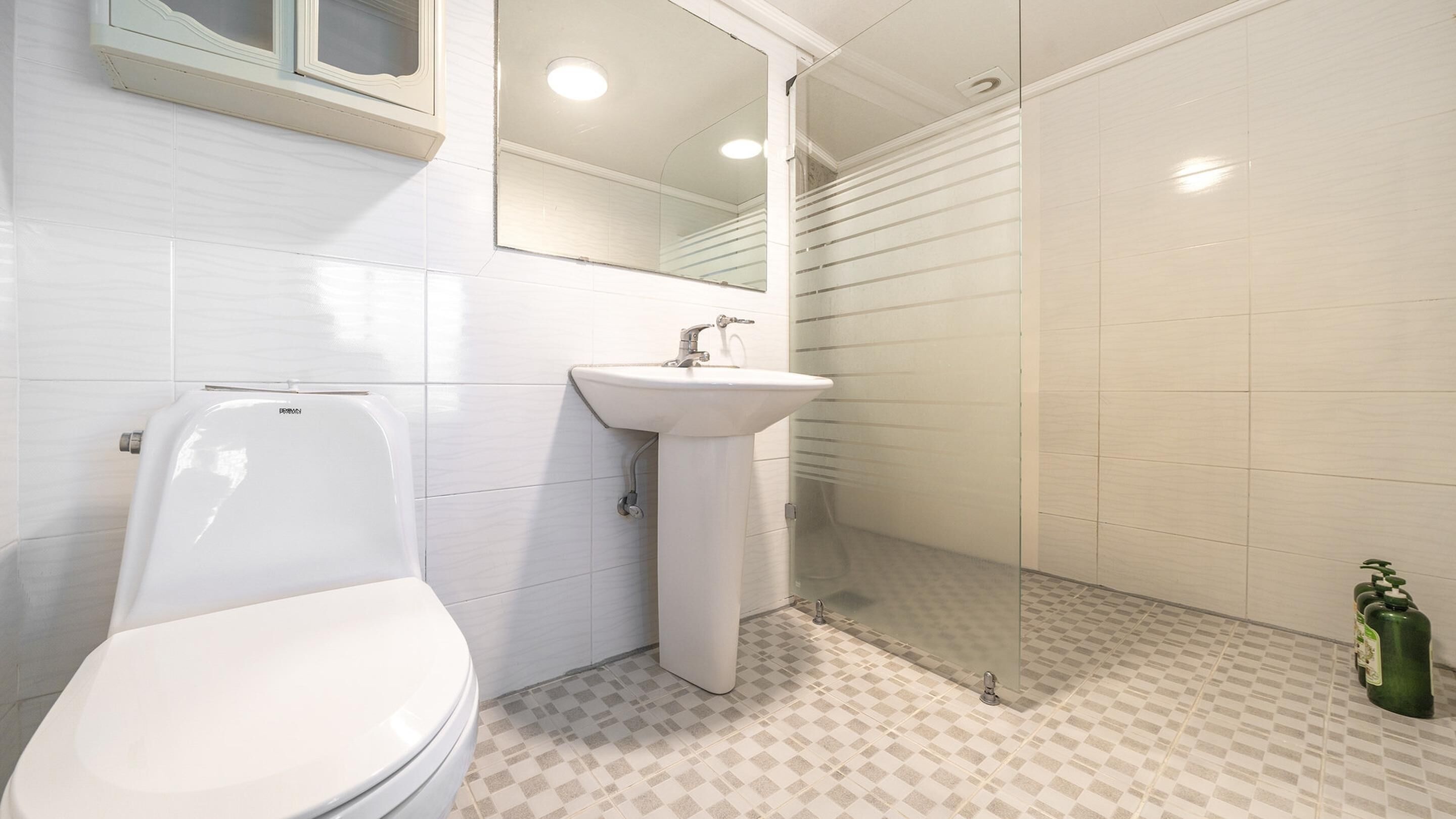 Een badkamer met toilet, wastafel en douche.