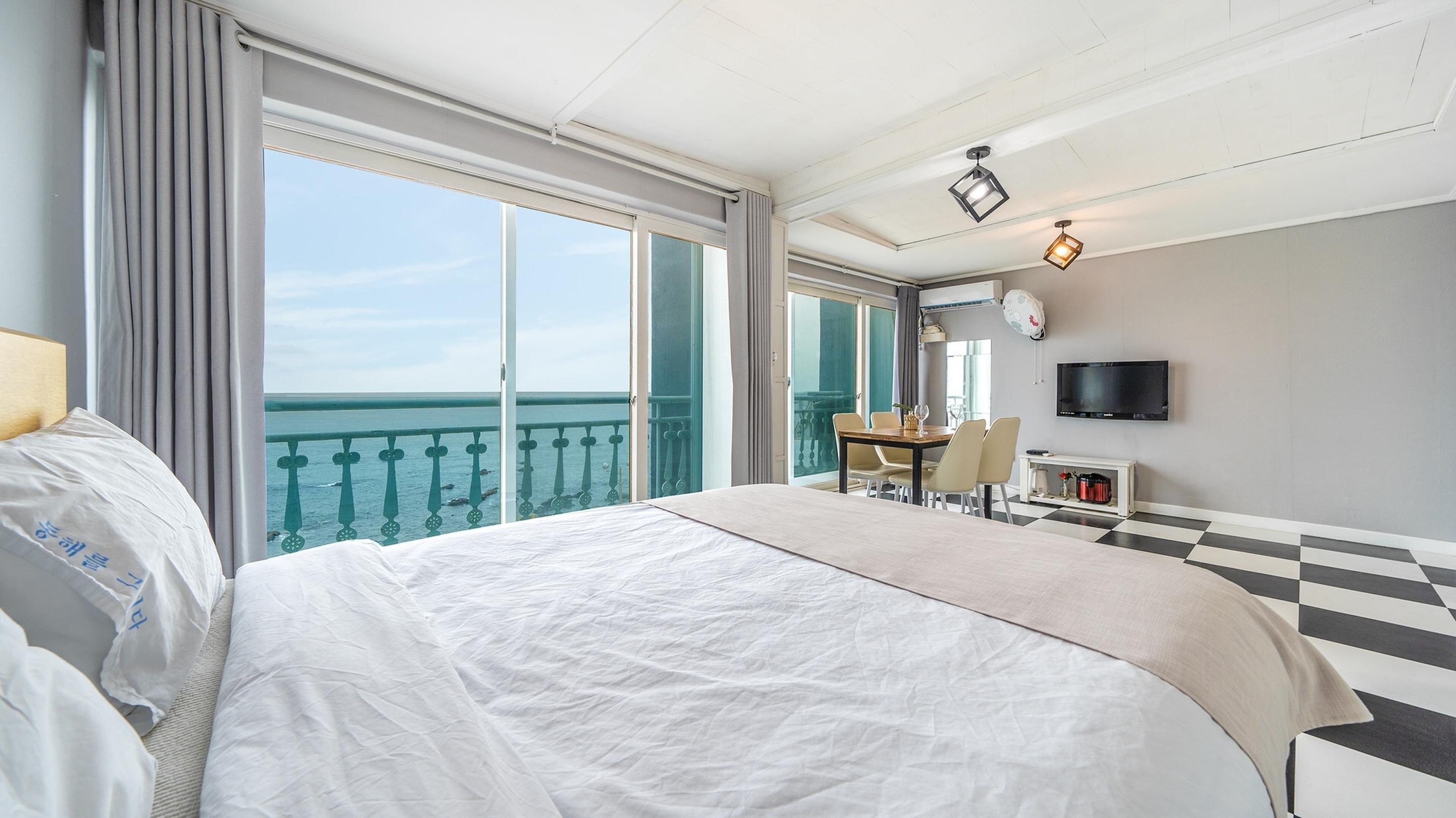 A hotel room with a large bed, a dining table, and a TV.