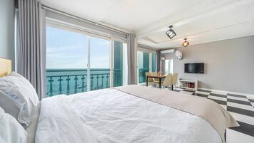 A hotel room with a large bed, a dining table, and a TV.