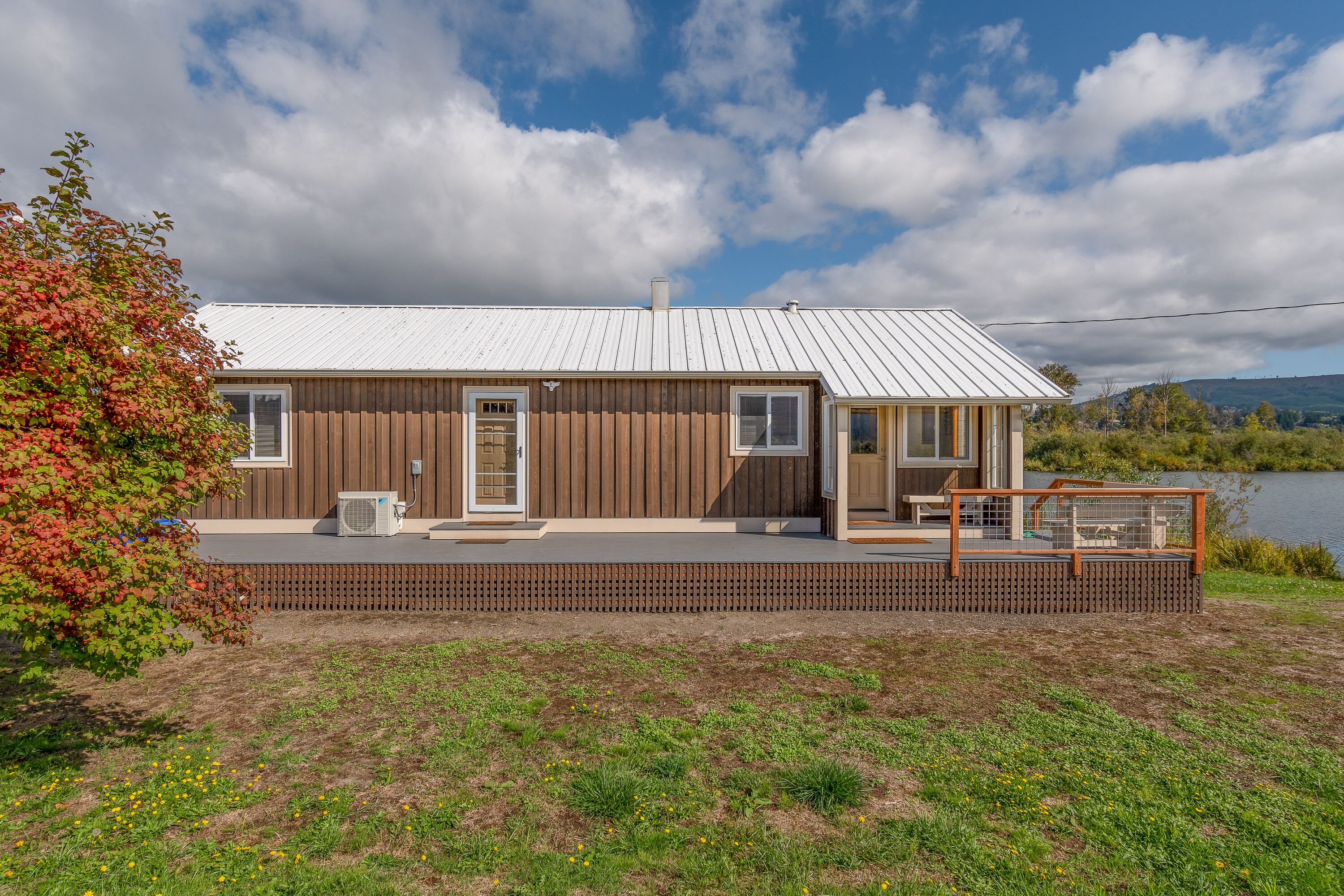 A modern house with a metal roof, wooden exterior, and a deck with a railing.