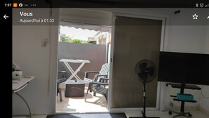 Ein Zimmer mit Schreibtisch, Stuhl, Fernseher und Ventilator.