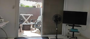 Ein Zimmer mit Schreibtisch, Stuhl, Fernseher und Ventilator.