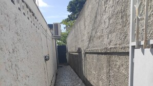 Ein schmaler Gang mit gefliestem Boden, der von strukturierten Wänden gesäumt wird und zu einem Tor führt.