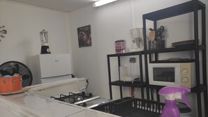 Eine Küche mit Gasherd, Mikrowelle, Kaffeemaschine und einem Regal mit Küchenutensilien.