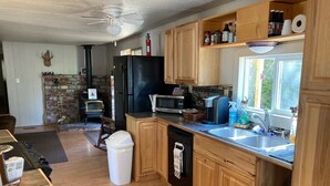 A kitchen with wooden cabinets, a black refrigerator, a microwave, and a sink.
