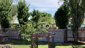 A backyard with a wooden table, a fence, and various plants.