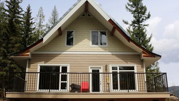 A two-story house with a balcony, large windows, and a gabled roof.