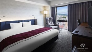 Habitación de hotel con cama, escritorio, silla y vista a la ciudad.