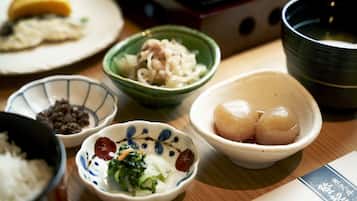 Una mesa con varios platos, incluyendo un bol de arroz, un bol de verduras y un bol de dumplings.