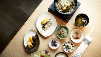 A wooden table with various dishes including a bowl of soup, a plate with a fish, and several small bowls with different foods.