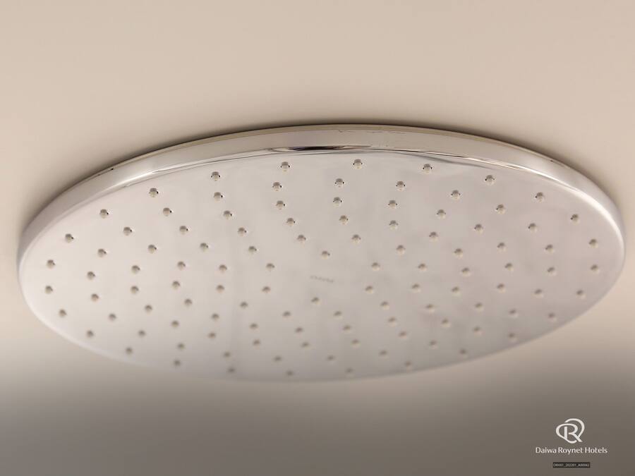 Teto com painel de metal perfurado, provavelmente parte de um sistema de chuveiro ou ventilação.