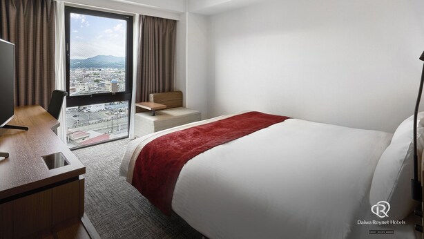 A hotel room with a bed, a desk, a chair, and a large window offering a city view. - Daiwa Roynet Hotel Yamagata-ekimae (Yamagata)