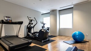 Gimnàs amb cintes de córrer, una màquina el·líptica, una bicicleta estàtica, una pilota d'exercici blava i estores de ioga.