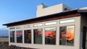 A modern building with large windows and a flat roof, situated on a grassy hill. - Peaceful SW-style ranch home in wine country (Elgin)