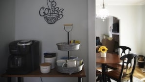 Et køkken med kaffemaskine, sukkerdåse og en dekorativ vægdekoration.