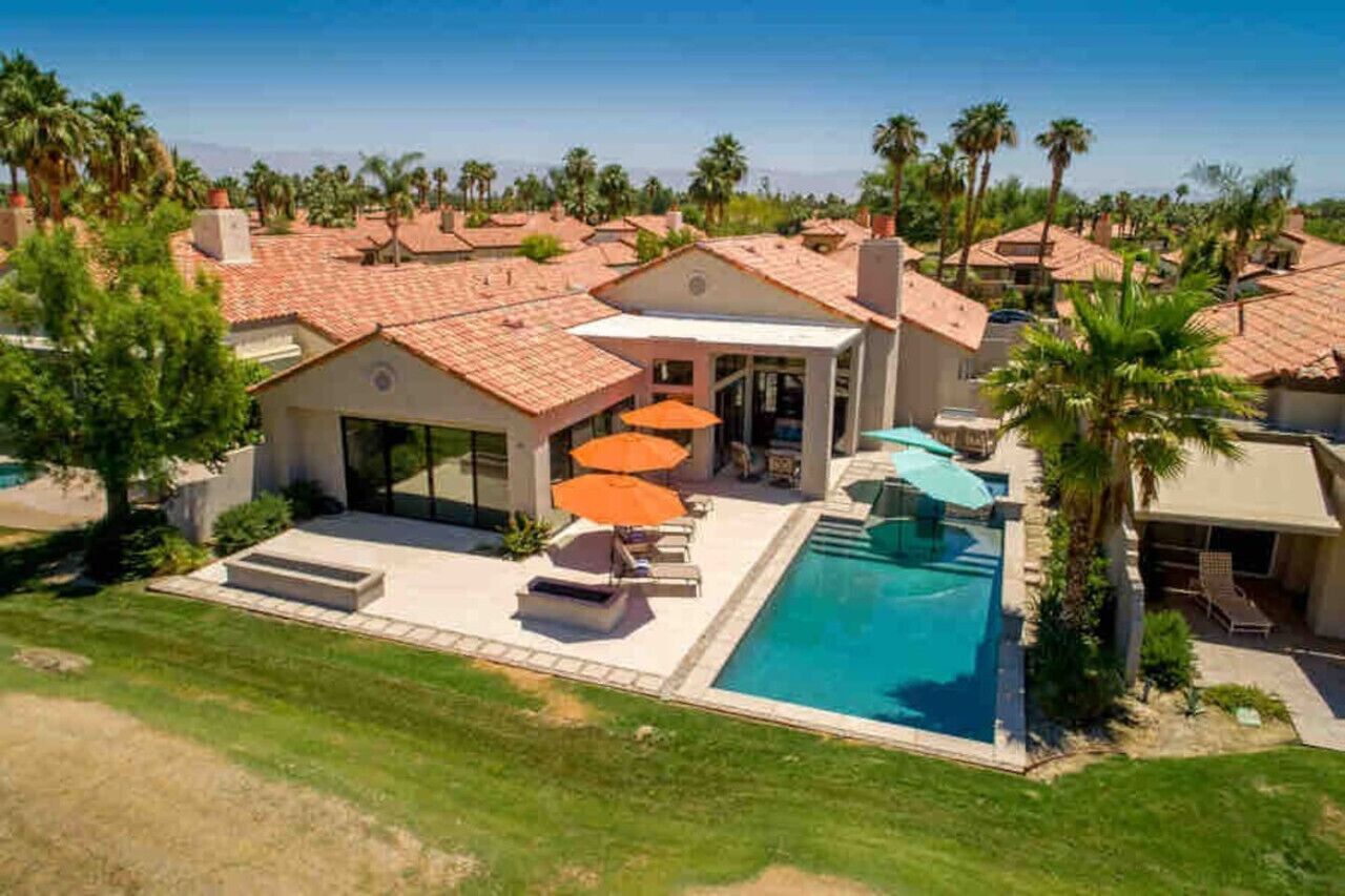 Propiedad residencial con piscina, patio con sombrillas y vistas del vecindario.