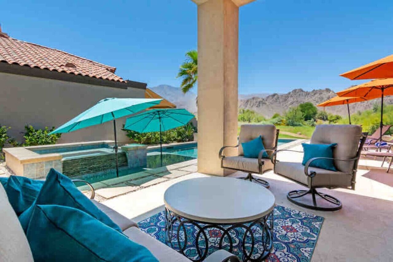 Eine Außenpatio mit Pool, zwei Liegestühlen und Sonnenschirmen.