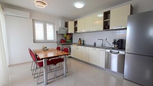 Uma cozinha moderna com eletrodomésticos de aço inoxidável, uma mesa de jantar com cadeiras vermelhas e uma janela com persianas.