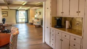 A spacious kitchen with wooden cabinets and a dining area with a patterned chair.