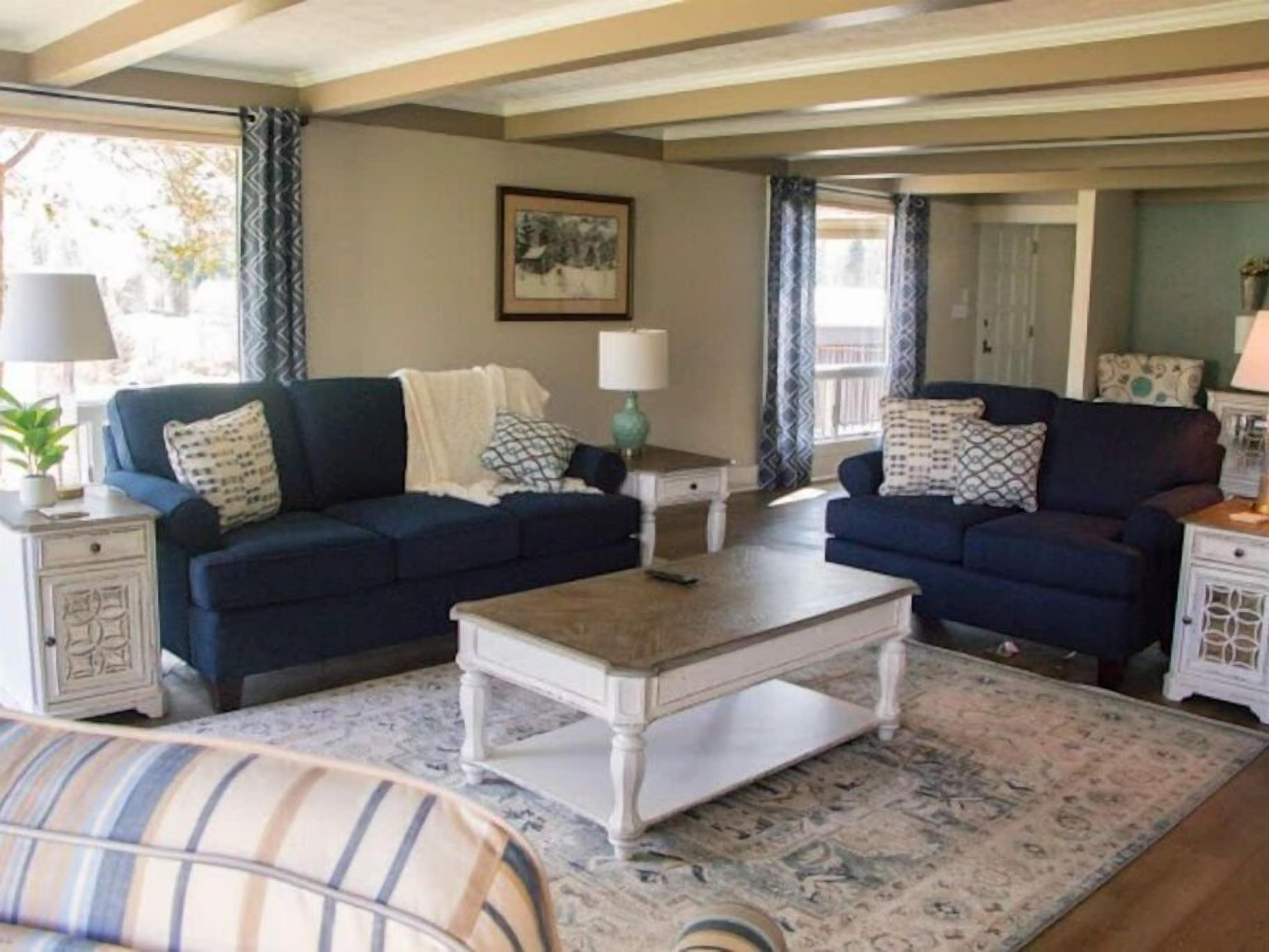 A living room with two dark blue sofas, a white coffee table, patterned rugs, and a framed picture on the wall.
