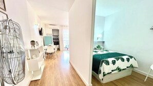 Et moderne hotelværelse med seng, skrivebord, stol og et stort vindue.