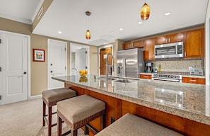 A kitchen with a granite countertop, stainless steel appliances, and wooden cabinets.