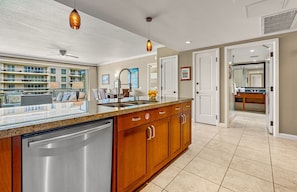 A modern kitchen with a large island, stainless steel appliances, wooden cabinets, and pendant lighting.