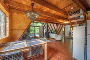 Une cabane en bois spacieuse comprenant un coin repas, une cuisine et un espace salon.